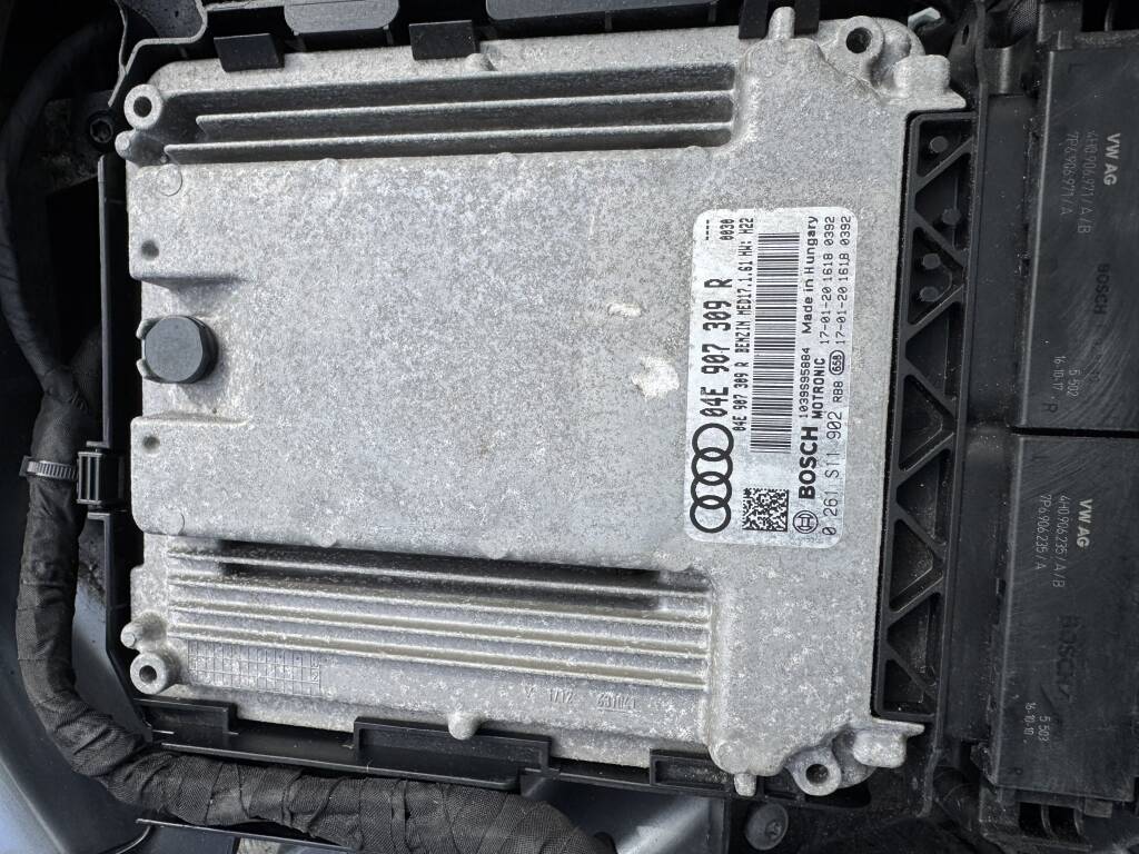 Technician tuning Audi ECU with laptop and diagnostics tools.